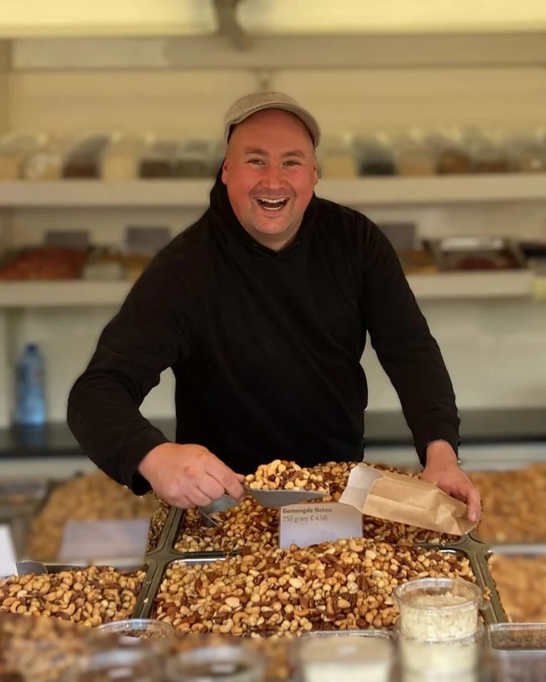 Fedor schept gemengde noten in een papieren zak aan de marktkraam.